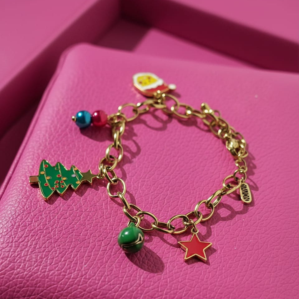 Pulsera de eslabones dorada con colección de charms de Navidad esmaltados (árbol, estrella roja, Santa Claus, cascabeles) sobre fondo rosa. Joyería festiva de alta calidad.